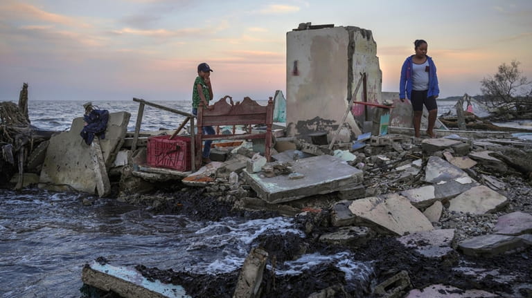 Yahir Mayoral and Emily Camacho walk amid the rubble of...