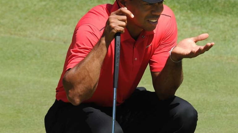 Tiger Woods lines up a putt on the fourth green...