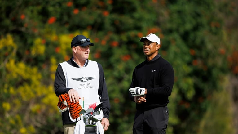 Tiger Woods talks with caddie Joe LaCava on the fourth...