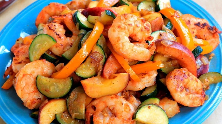 Shrimp, zucchini, red bell peppers and peaches are seared with...