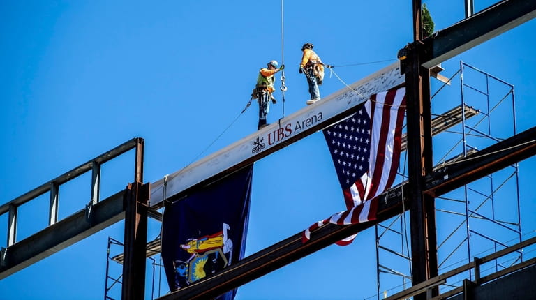Construction workers install the beam at the highest point of...