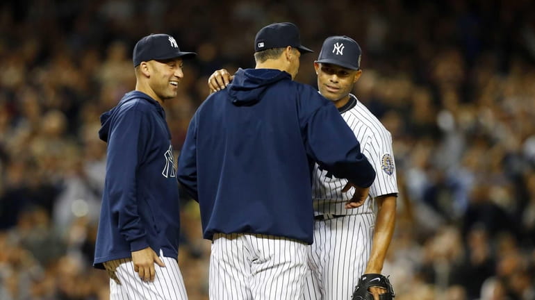 Mariano Rivera of the Yankees hugs teammate Andy Pettitte, with...