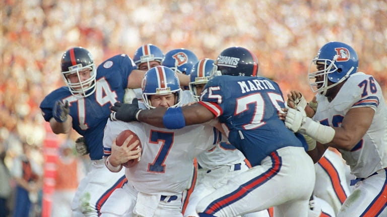 Broncos quarterback John Elway gets sacked for a safety by...