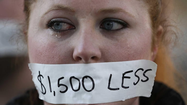 A silent protester cries while wearing a sticker over her...