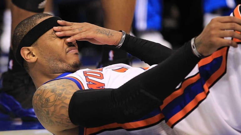The Knicks' Carmelo Anthony reacts after falling out of bounds...