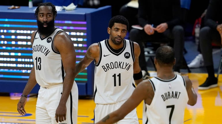 Nets guard Kyrie Irving (11) gathers with guard James Harden...