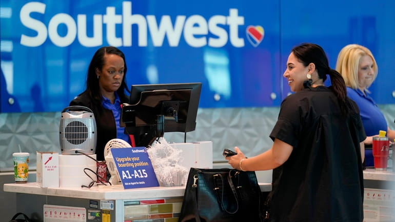 A Southwest airlines customer service representative, left, assists a traveler...