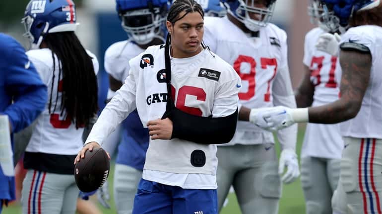 Giants safety Dane Belton watches practice with his left arm...