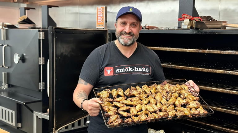 Manny Voumvourakis hoists a batch of smoked chicken wings at...