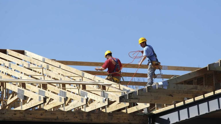Carpenters work on the roof of an affordable housing project...