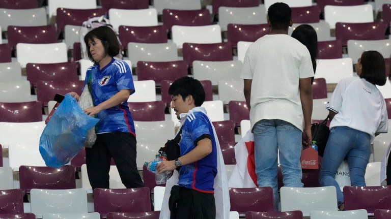 Japan supporters clean the stands at the end of the...