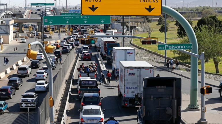 Cars and trucks line up to enter Mexico from the...