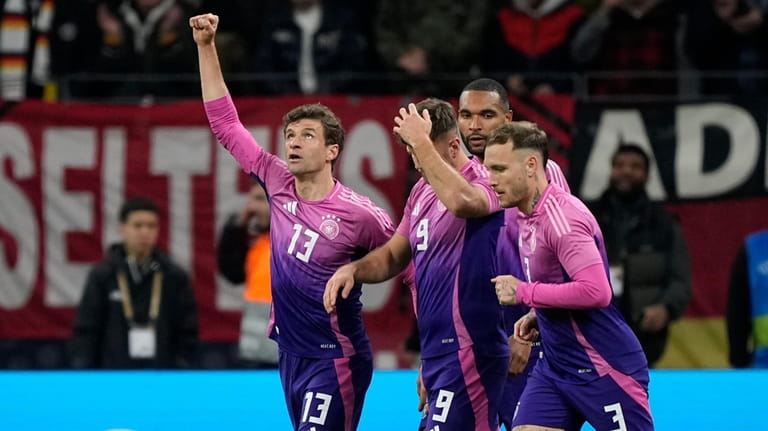 Germany's Thomas Mueller, left, celebrates after Niclas Fuellkrug, center, scored...