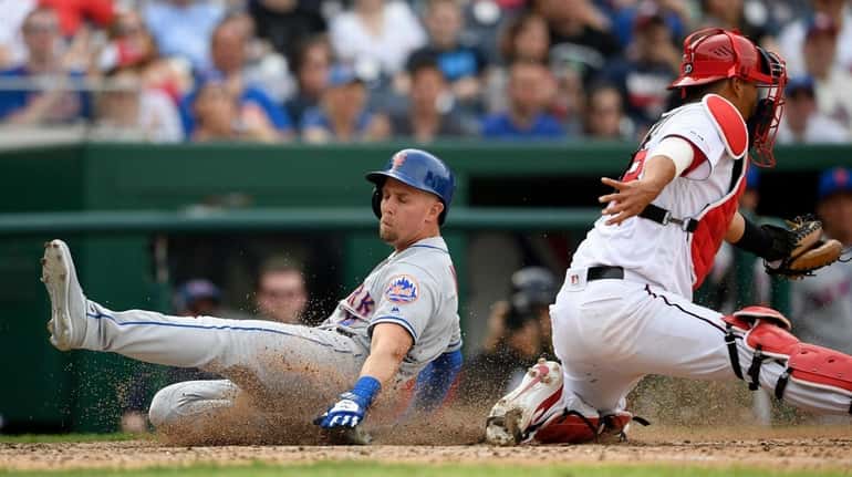 Mets' Jeff McNeil, left, slides home to score a run...