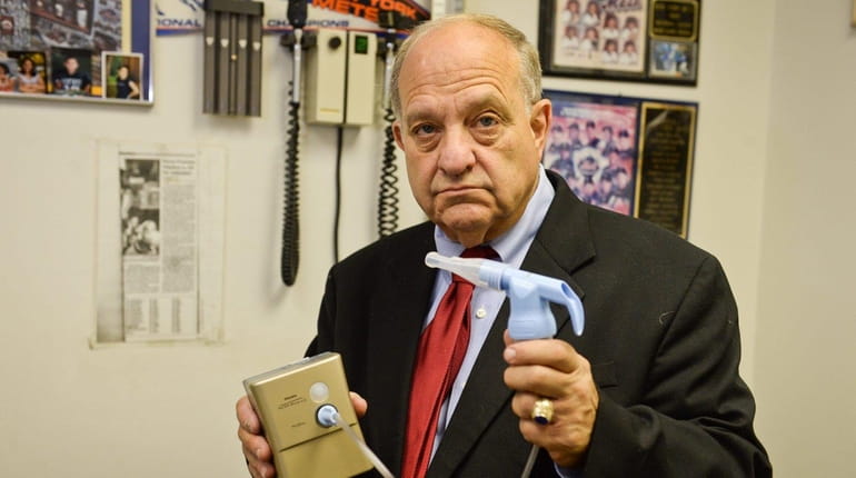 Asthma specialist Dr. Harvey Miller stands with a nebulizer machine...