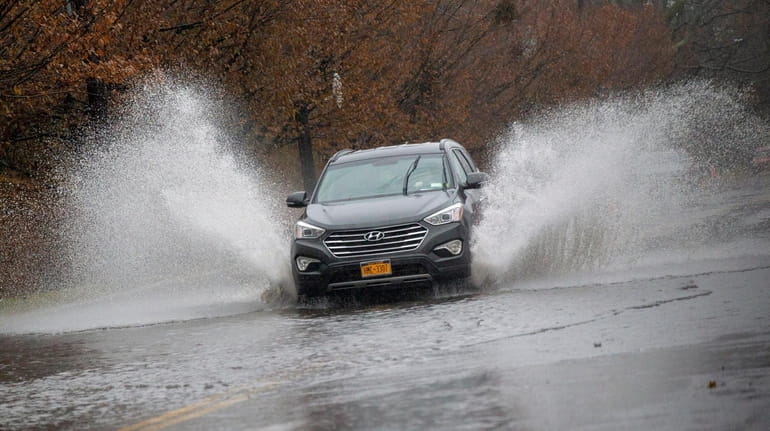 A car navigates a flooded portion of Commercial Avenue in Garden...