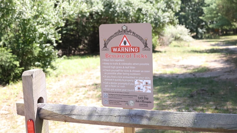 A sign warnw of ticks at the entrance to a trail...