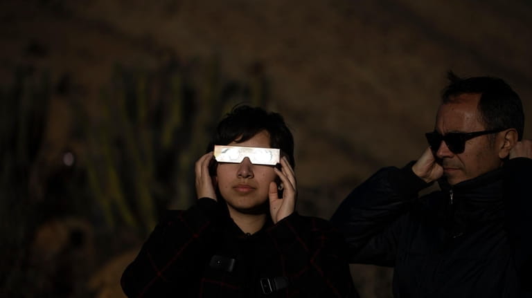 People watch a total solar eclipse in La Higuera, Chile,...