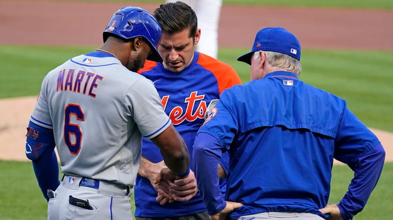 The Mets' Starling Marte is checked by a trainer with manager...