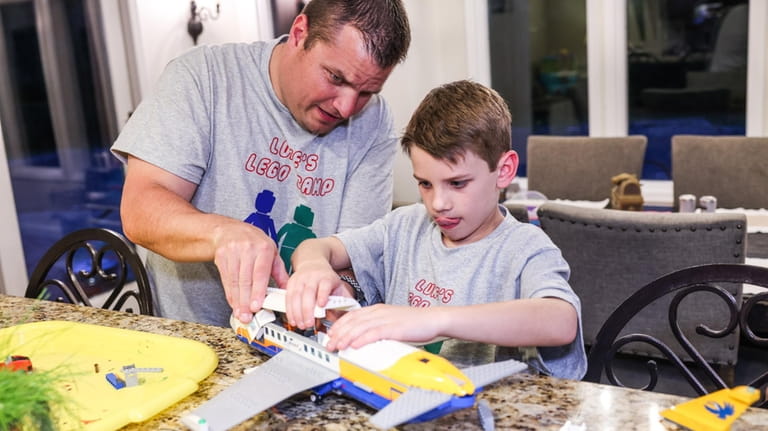 Luke Harmon, 8, builds a Lego airplane with help from...
