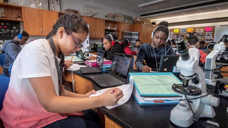 Seventh-grade honors Earth Science student Clohie Clarke, left, uses a...