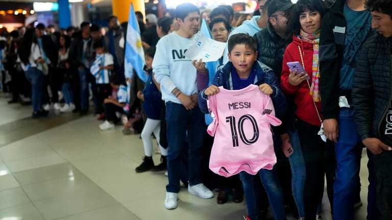 A child holds a of T-shirt of Inter Miami soccer...