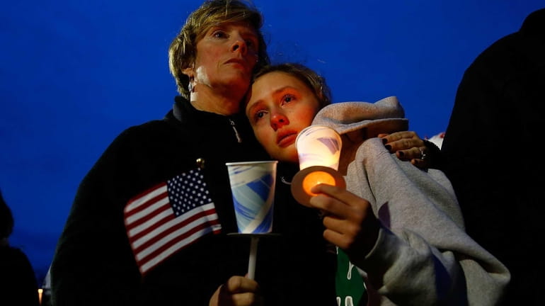 A young girl cries with her mother during the vigil...