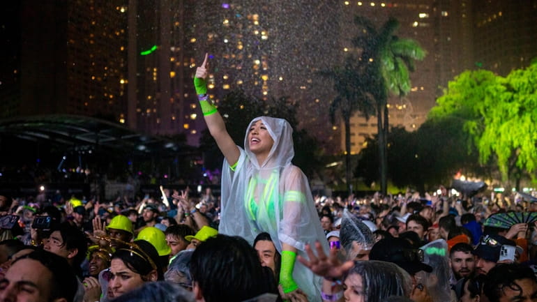 A woman reacts to music as it rains during the...