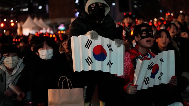 South Korean soccer fans react as they watch a live...