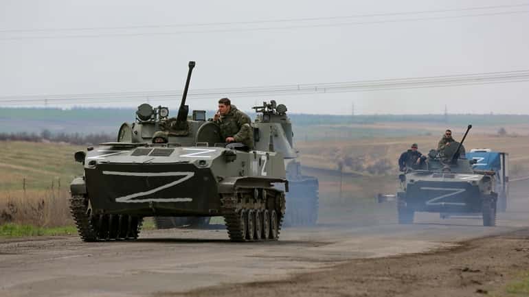 Russian military vehicles move on a highway in an area...