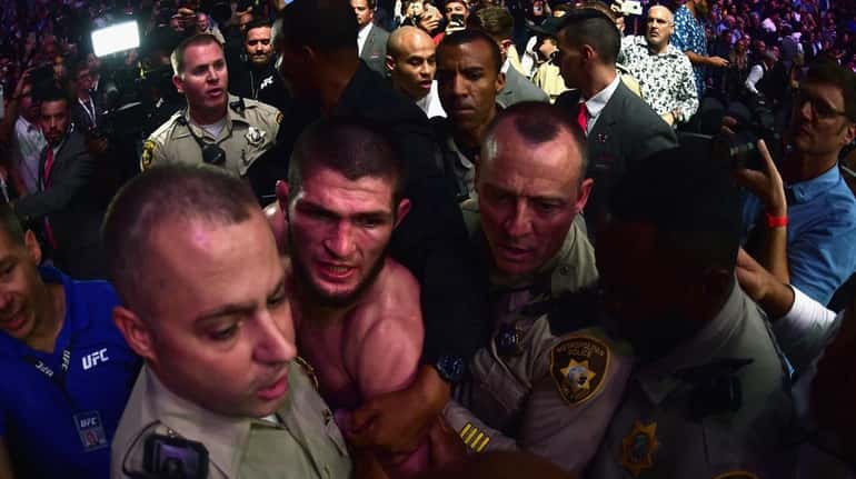 Khabib Nurmagomedov is escorted out of the arena after defeating...