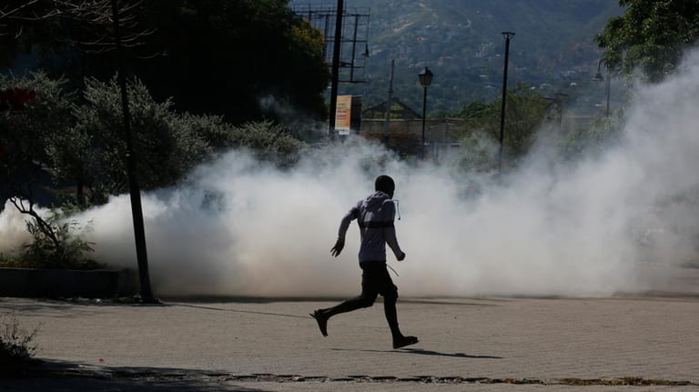 A man runs for cover as riot police launch tear...