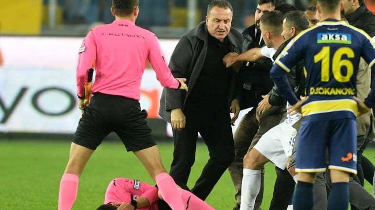 Referee Halil Umut Meler holds his face as he lies...