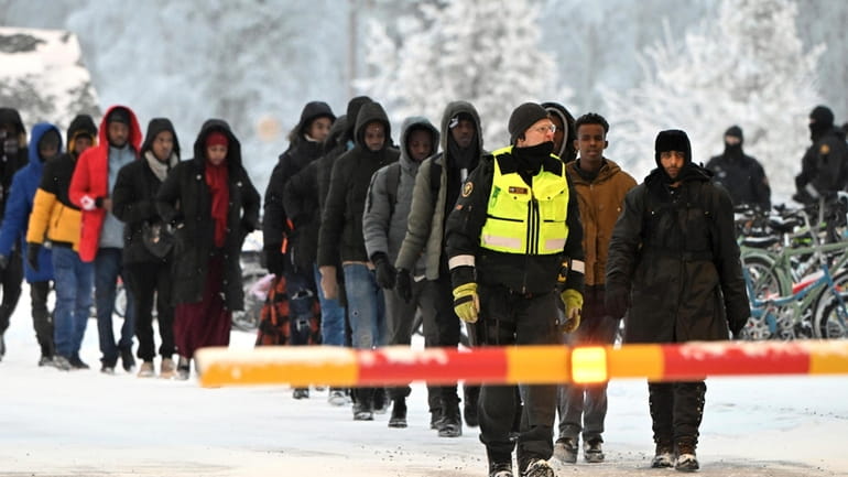 Finnish Border Guards escort migrants at the international border crossing...
