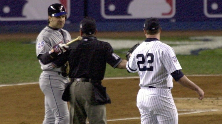 The Mets' Mike Piazza, left, points the end of his...