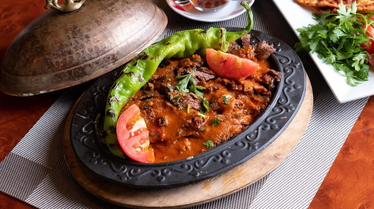 Iskender kebab, slices of lamb doner over pita bread and...