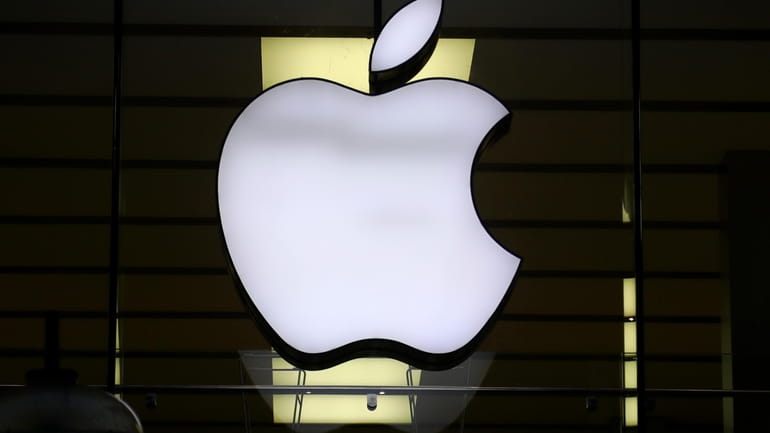 The Apple logo is illuminated at a store in the...