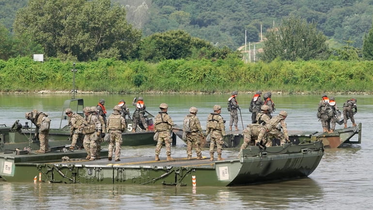 U.S. and South Korean soldiers try to connect a floating...