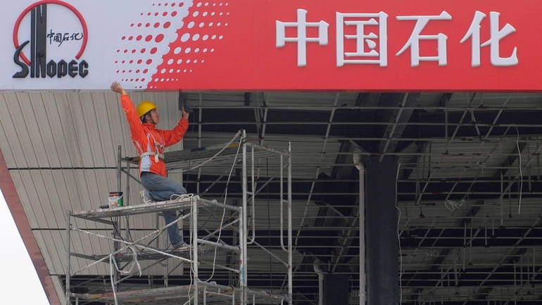 A Chinese worker labors on a Sinopec sign board at...