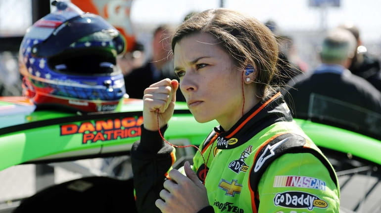 Danica Patrick removes her earplugs by her car on pit...