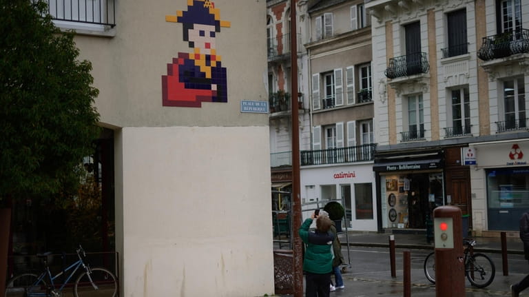 A boy takes a photo of a mosaic by French...