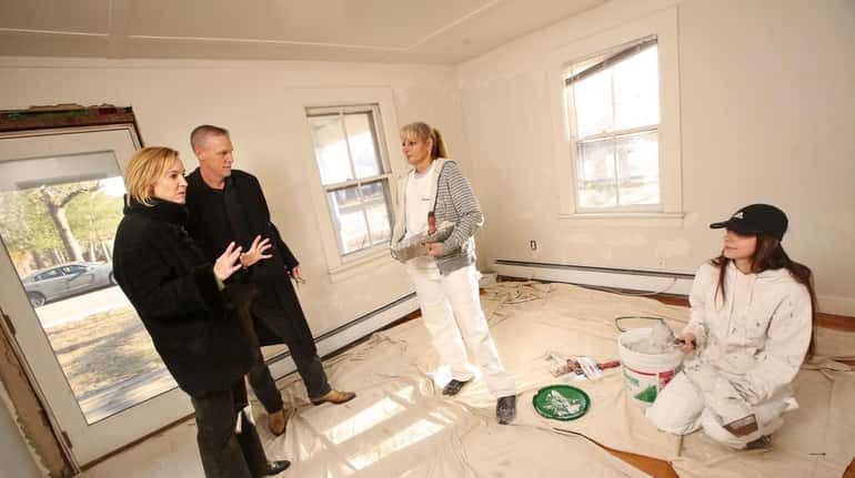 Husband and wife real estate agents Susan and Richard Connelly, left, talk with painters...