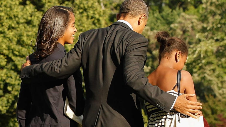 President Barack Obama and his daughters Malia and Sasha walk...