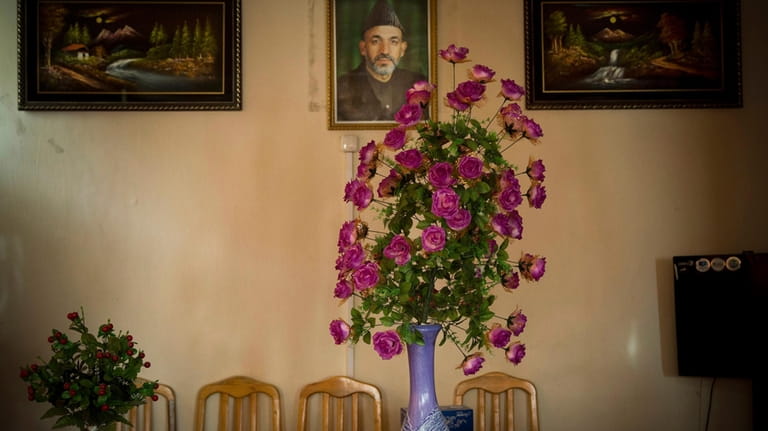 A picture of Afghan President Hamid Karzai hangs on a...
