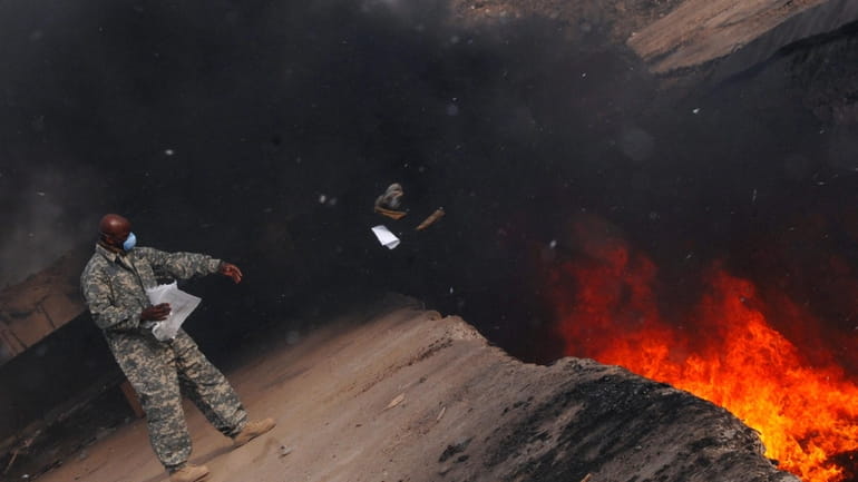 An Air Force service member tosses items into a burn...