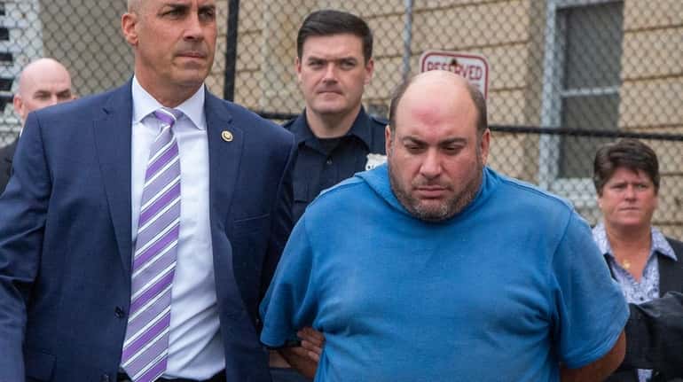 David Cahoon of Dix Hills is escorted out of Nassau County...