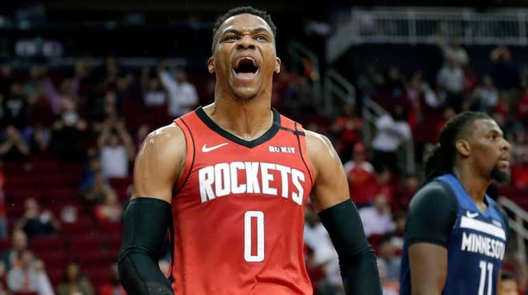 Rockets guard Russell Westbrook reacts after a dunk, next to Timberwolves...