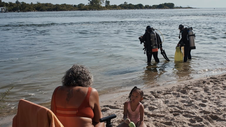 A family spends time on the beach as scuba divers,...