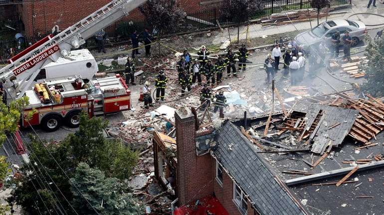 Emergency service personnel work at the scene of a house...