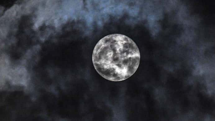 A supermoon briefly breaks through the clouds over Wantagh on...